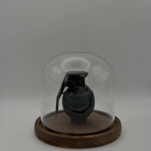 Oggetto d'arredamento moderno: granata decorativa nera in cloche di vetro su base in legno scuro.