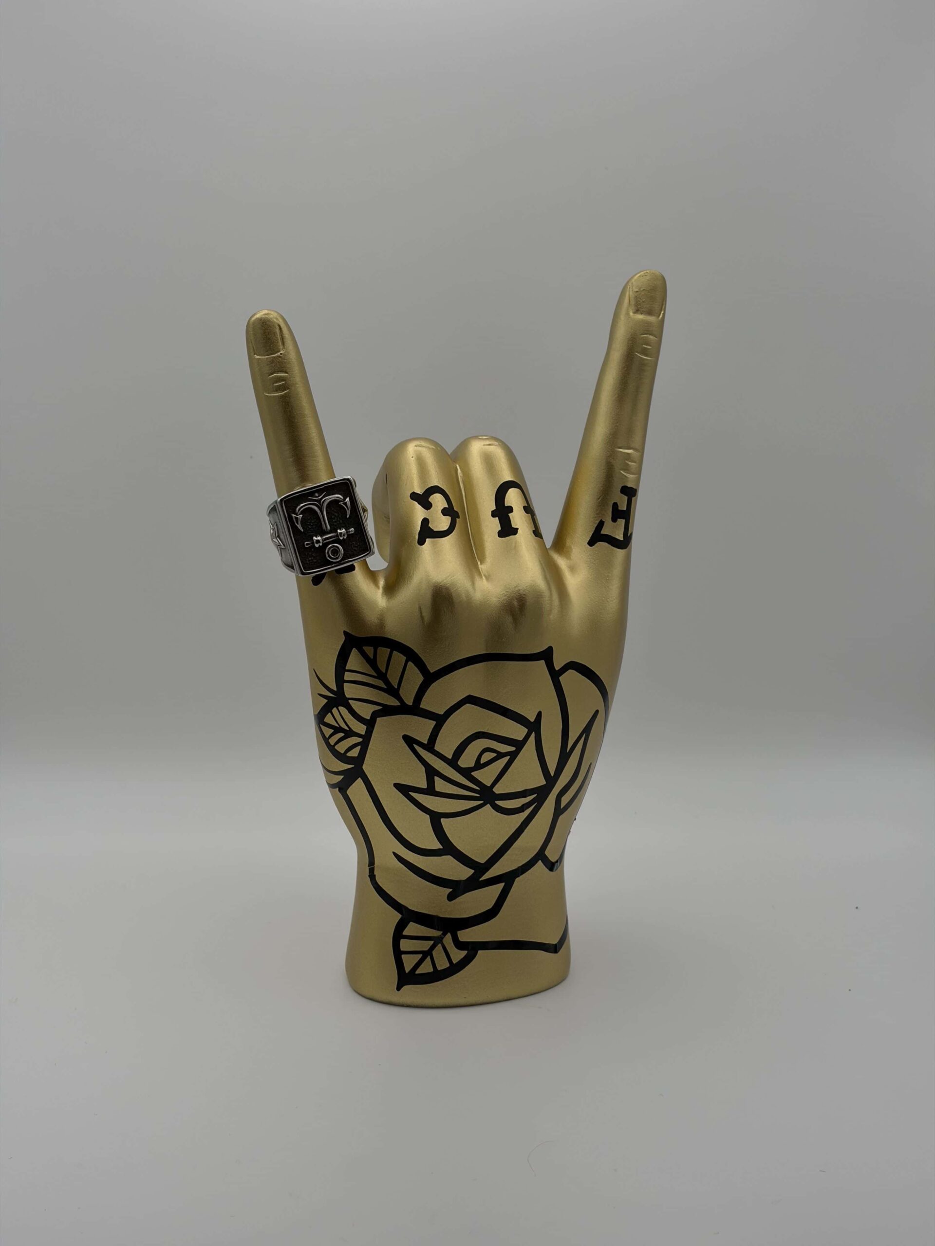 Mano porta anelli design tattoo oro stile rock on con tatuaggi neri